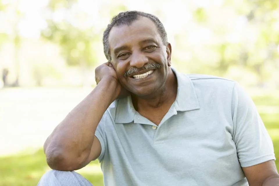un homme souriant avec sa main sur sa tête